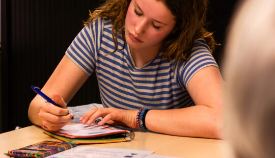 onge vrouw volgt een training tot digicoach en schrijft notities tijdens een Wark-DIVA bijeenkomst.